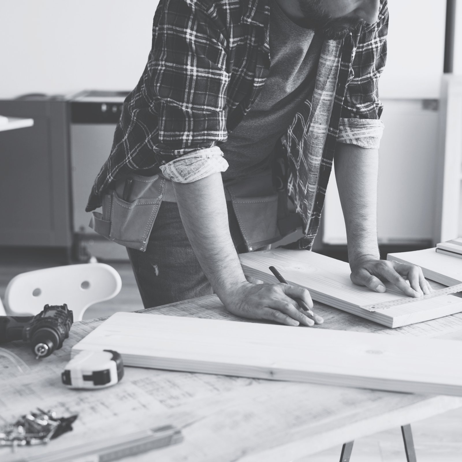 A craftsman carefully measuring and marking a piece of wood before cutting