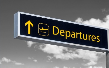 Airport departures sign with a plane flying overhead