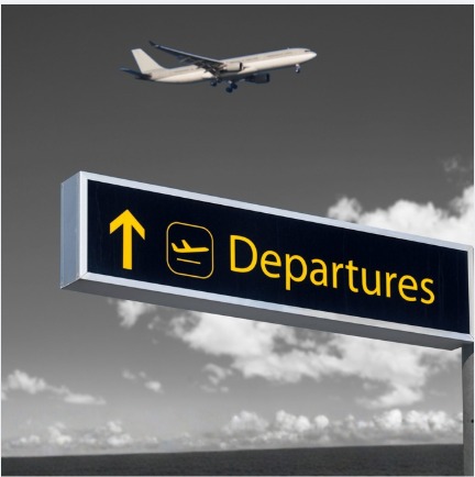 Airport departures sign with a plane flying overhead