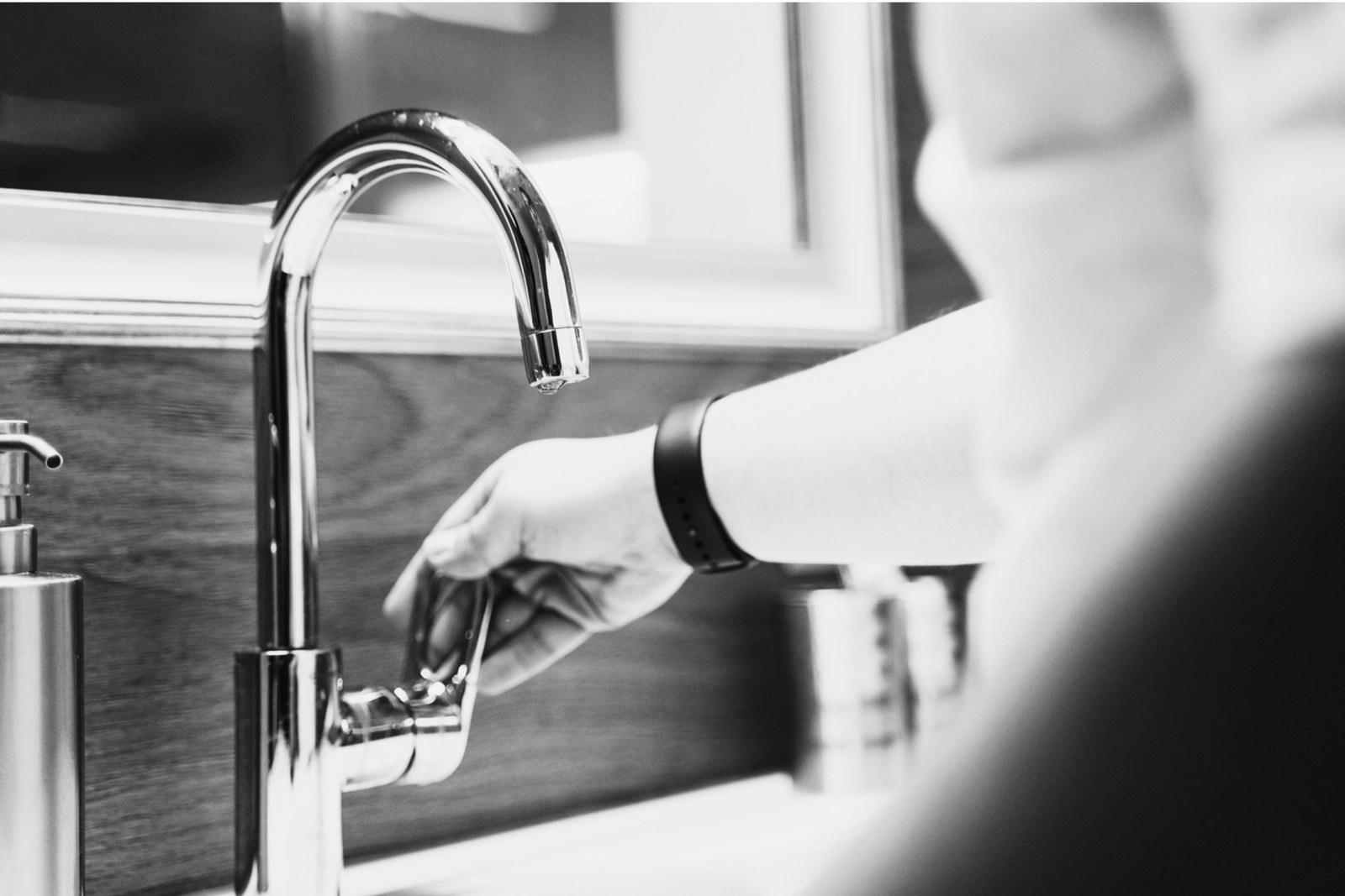 A hand turning on a chrome tap
